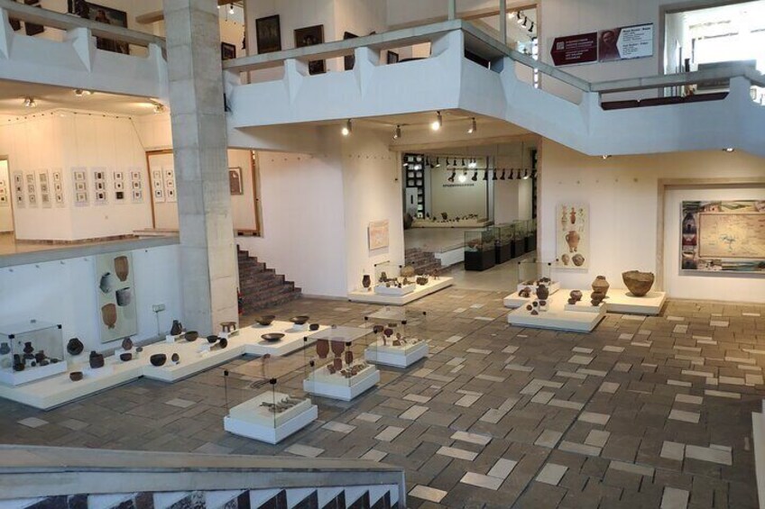 An art gallery with multiple levels, displaying various sculptures and artworks on pedestals. 5