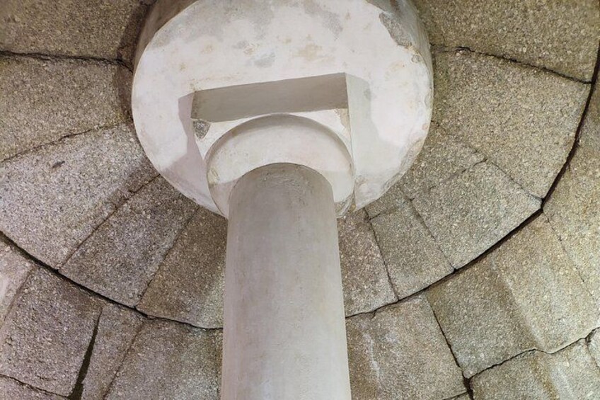 A stone structure with a central column and a circular pattern around it. 2