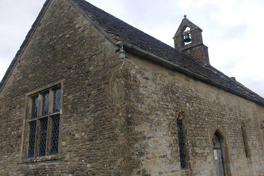 A stone building with a bell tower, a large window with a grid pattern, and a door. 5