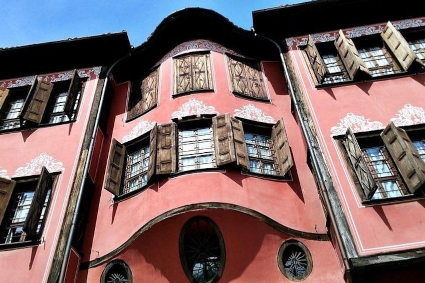 A building with a curved facade, wooden shutters, and decorative window frames. 5