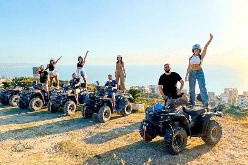 People on ATVs on a hill with a cityscape in the background. 1