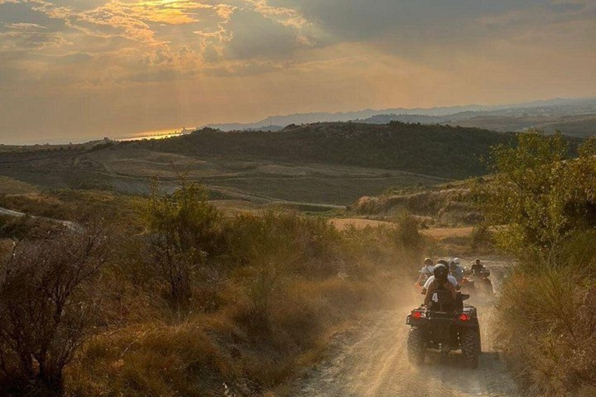 A group of people riding off-road vehicles on a dirt path through a hilly landscape. 4