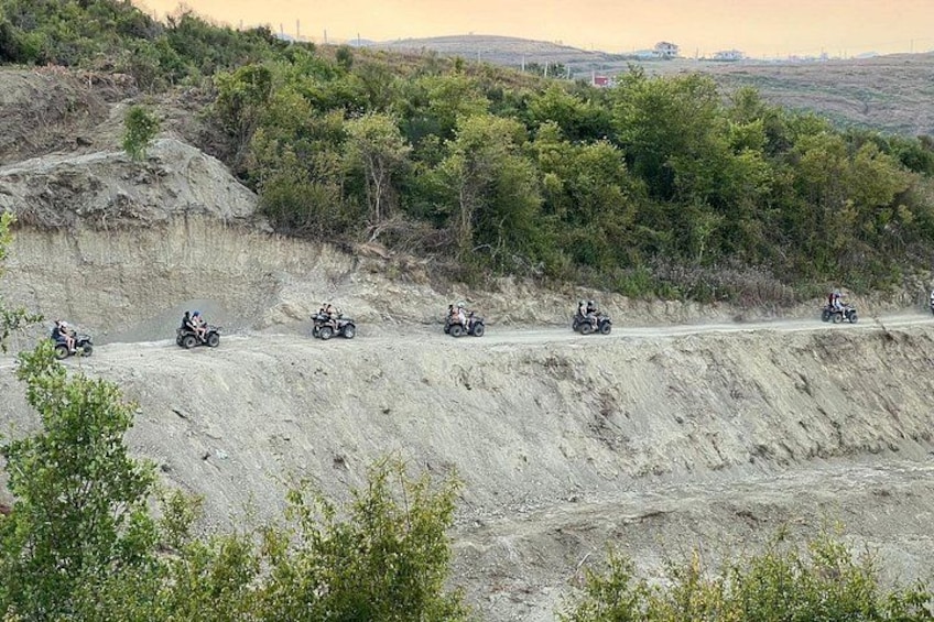 A group of off-road vehicles on a dirt road surrounded by hills and sparse vegetation. 3
