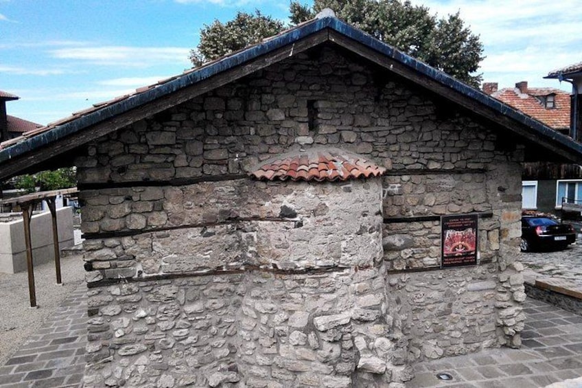 A stone building with a tiled roof, a sign, and a parked car. 3