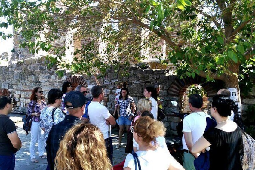 A group of people gathered around a stone structure with an arched doorway, possibly a historical site or monument. 5
