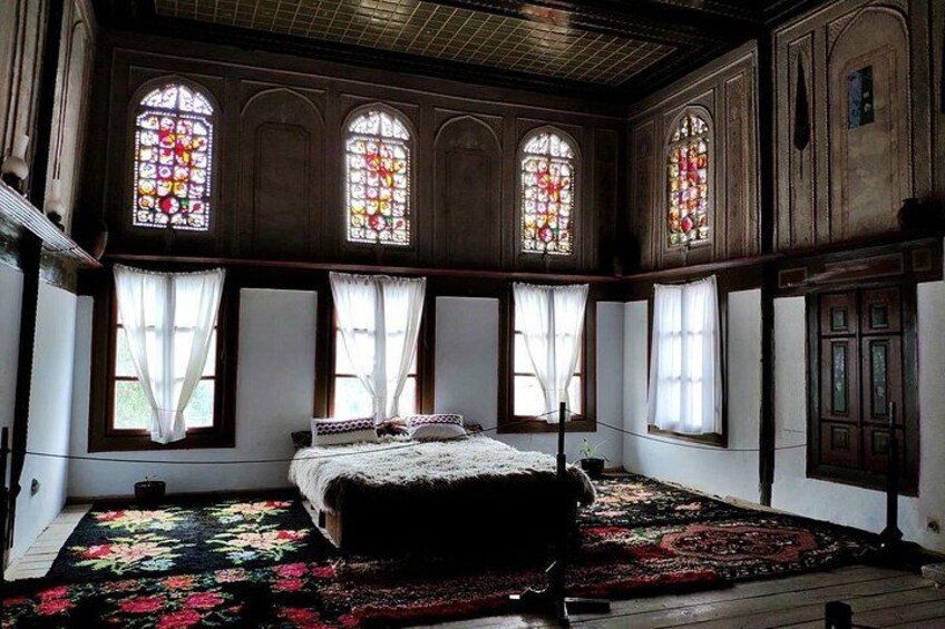 A room with a bed, stained glass windows, and a patterned rug. 3