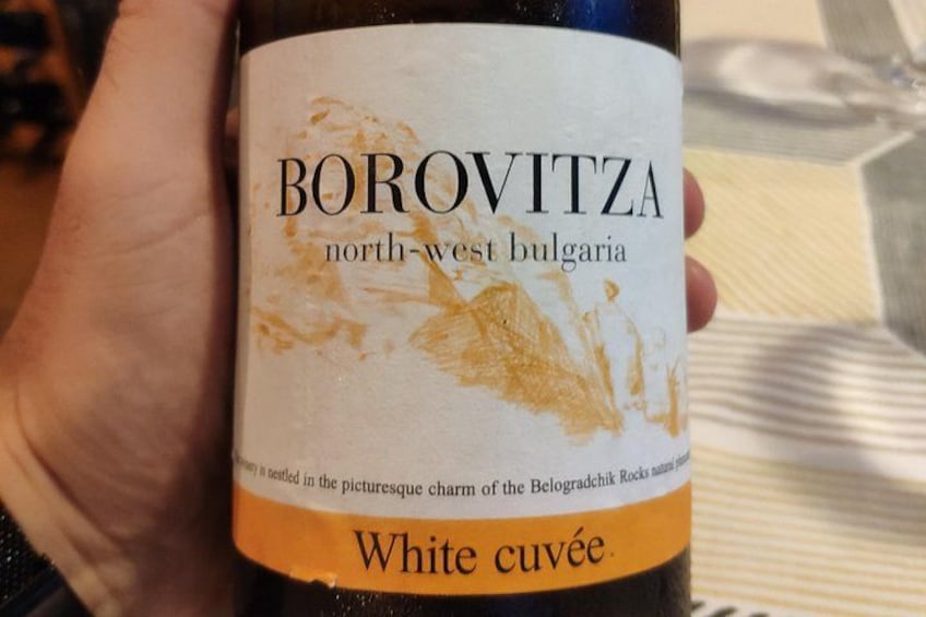 A hand holding a Borovitza wine bottle with a label that reads 'north-west bulgaria' and 'White cuvée.' 1