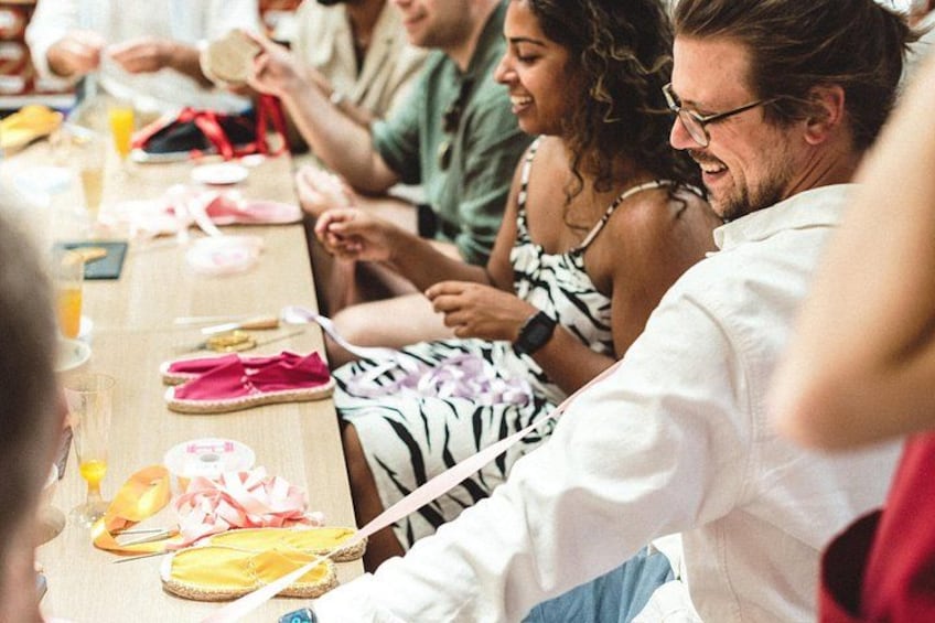A group of people sitting at a long table with food and drinks. 1