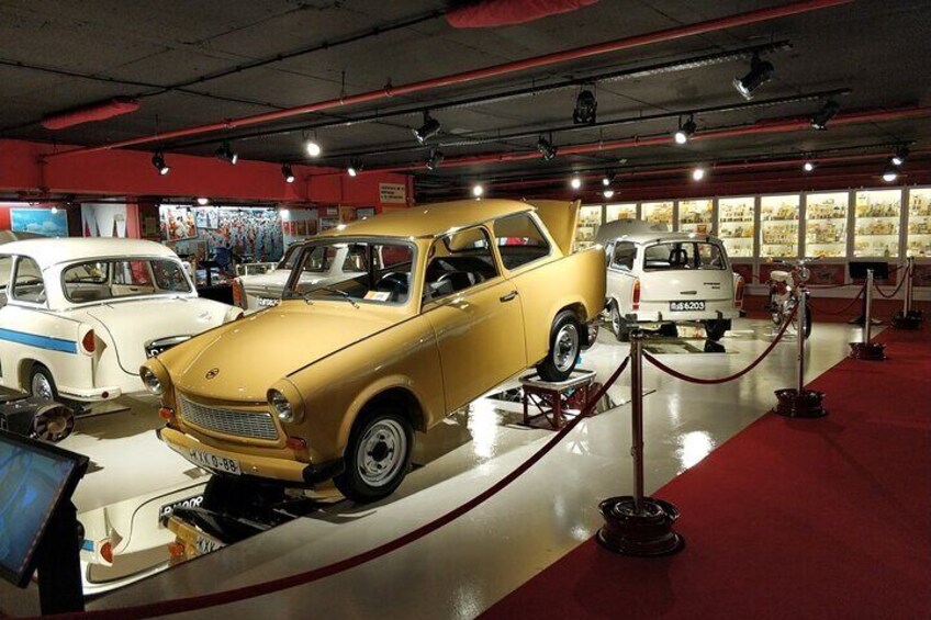 A vintage car exhibition with a yellow car prominently displayed. 5