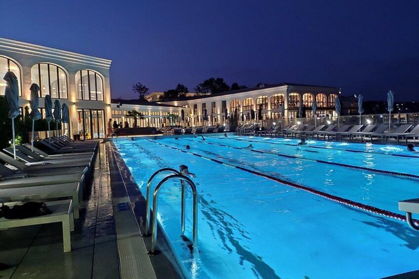 A swimming pool at night with lounge chairs and umbrellas. 3