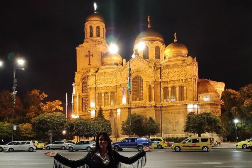 A large, illuminated church with multiple domes and a cross on the facade. 4
