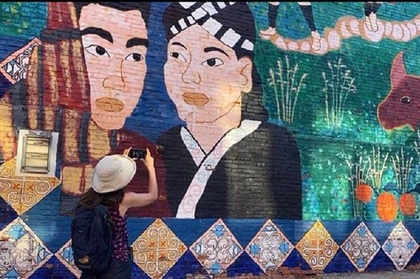 Un mural con dos rostros grandes, una persona tomando una fotografía y motivos decorativos. 4
