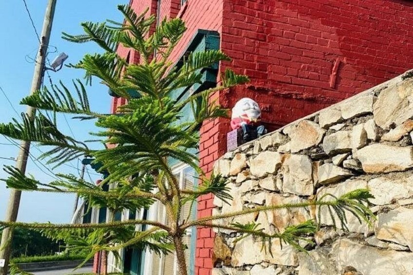 Un edificio de ladrillo rojo con un muro de piedra, una palmera y una persona trabajando en el muro. 2