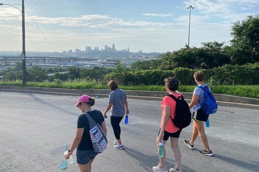 Four people walking on a road with a city skyline in the background. 2
