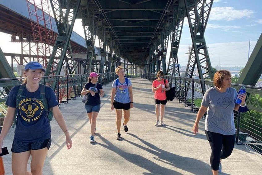 People walking on a bridge with metal beams and a concrete walkway. 4