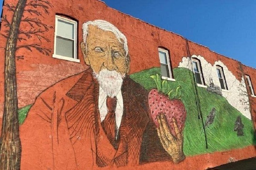 A mural on a building with a man holding a strawberry. 1
