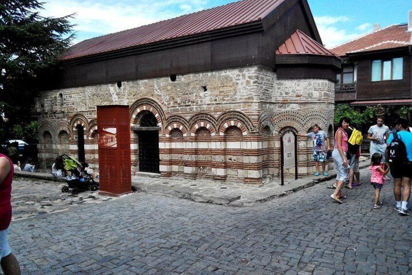 A historic stone building with arched doorways and a red roof. 5