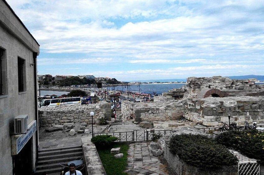 A historical site with ruins, a staircase, and a view of the sea. 4