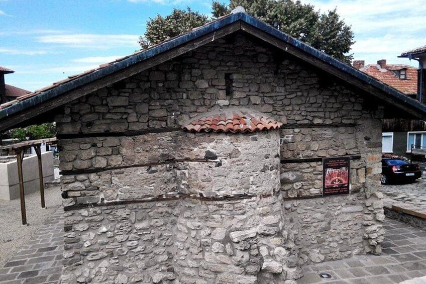 A stone building with a tiled roof, a sign, and a parked car. 3
