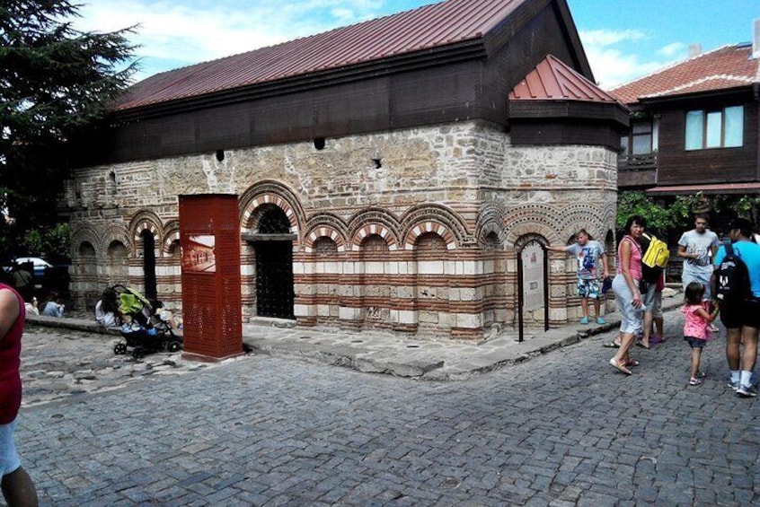 A historic stone building with arched doorways and a red roof. 5
