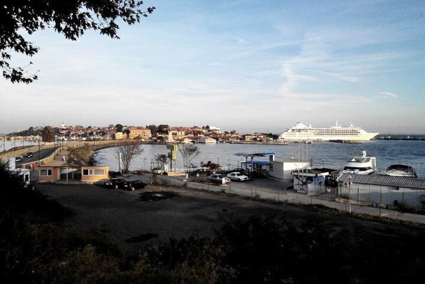 A harbor with a large cruise ship, boats, and buildings along the waterfront. 1