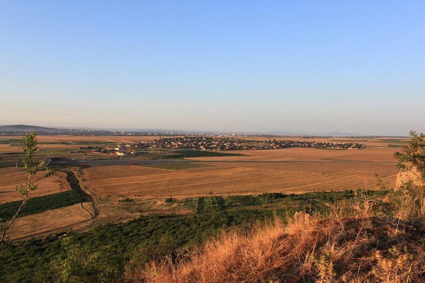A rural landscape with fields, a small settlement, and a clear sky. 4