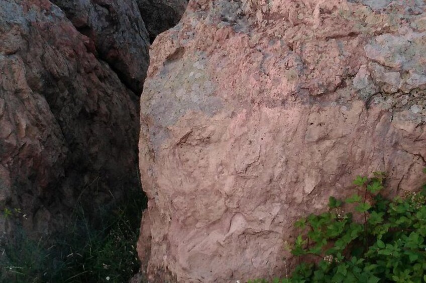 A rocky terrain with a large boulder and a narrow crevice. 1