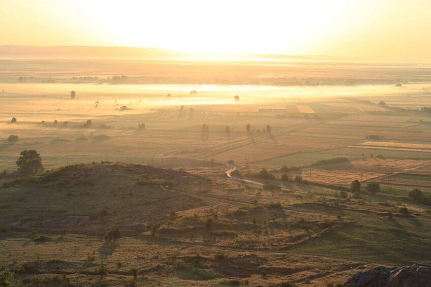 A rural landscape with fields, a winding road, and a distant horizon. 3