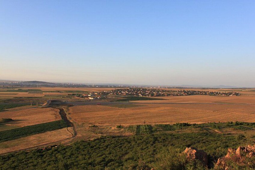 A rural landscape with fields, a small settlement, and distant hills. 2