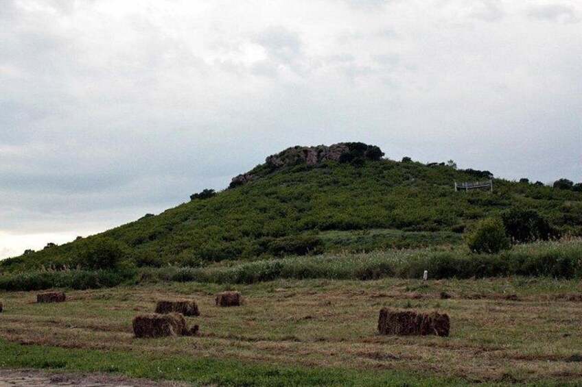 A grassy field with hay bales and a hill with a sign. 5