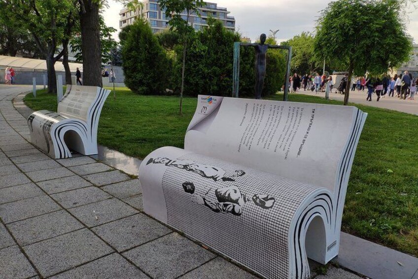 A park with benches covered in large sheets of paper. 1