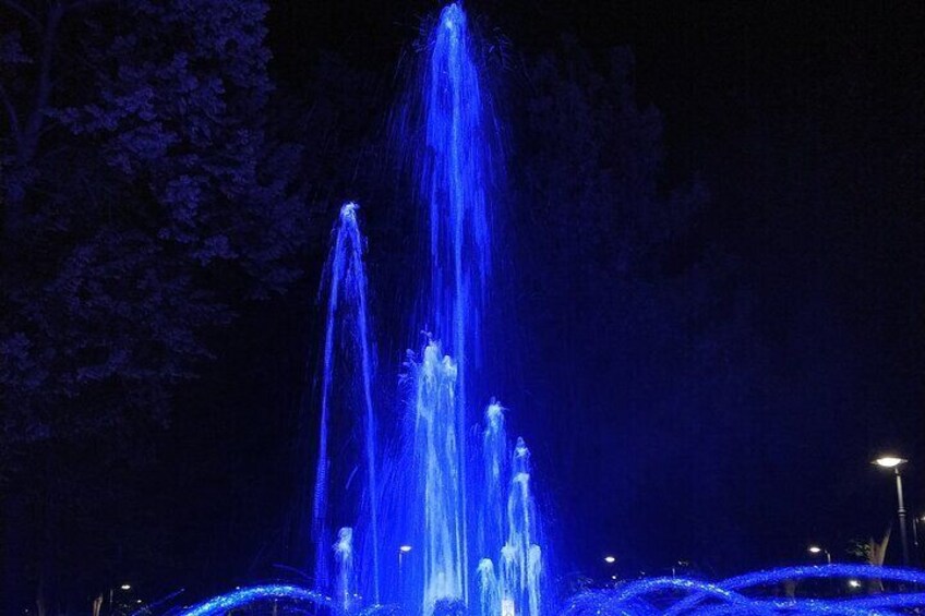 A fountain with water jets illuminated in blue at night. 5