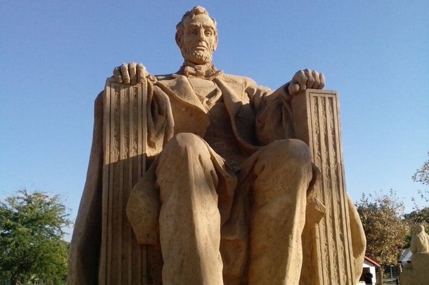 A large stone statue of a seated man with a beard, wearing a suit and holding a book. 4