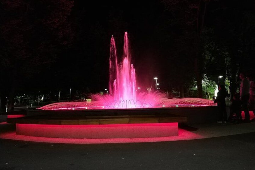 A fountain with pink lights at night. 2