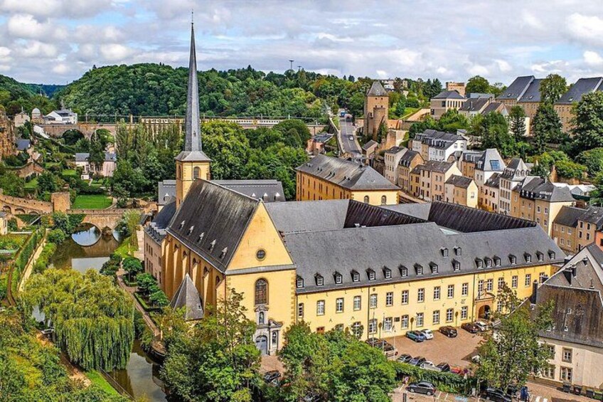 A historic town with a prominent church, a river, and surrounding greenery. 2
