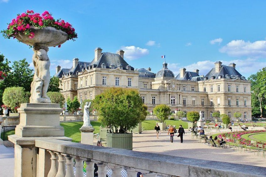 A historic building with a large garden, statues, and a fountain. 2