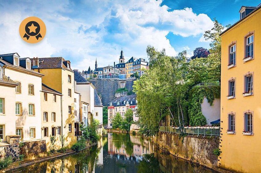 A river with buildings on either side, a bridge, and a hill with a tower in the background. 1