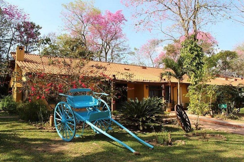 A blue cart in a garden with a building in the background. 1
