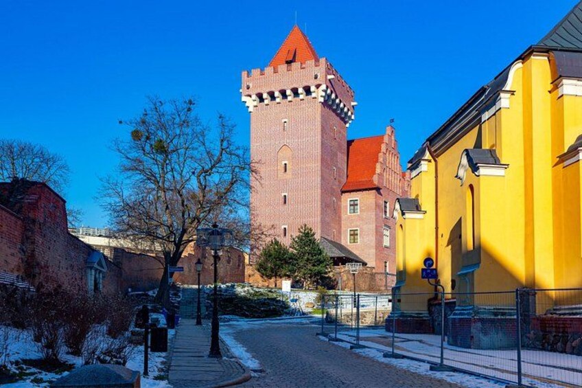 Una torre storica con tetto rosso, un edificio giallo e una strada innevata. 2