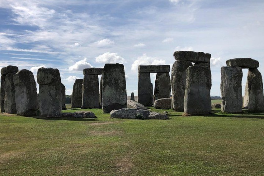 Stonehenge standing in a grassy field under a partly cloudy sky. 3