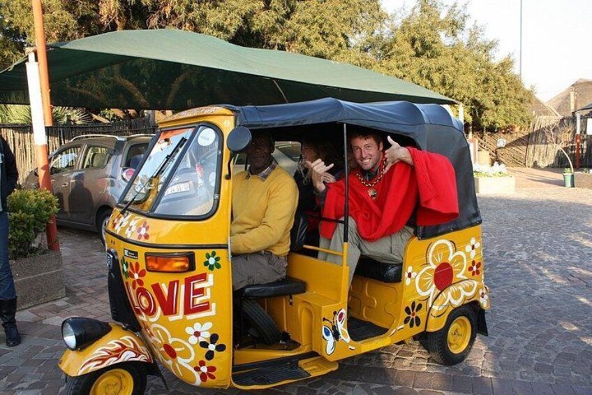 A yellow auto-rickshaw with floral decorations and the word 'LOVE' on the side, parked on a cobblestone street. 3