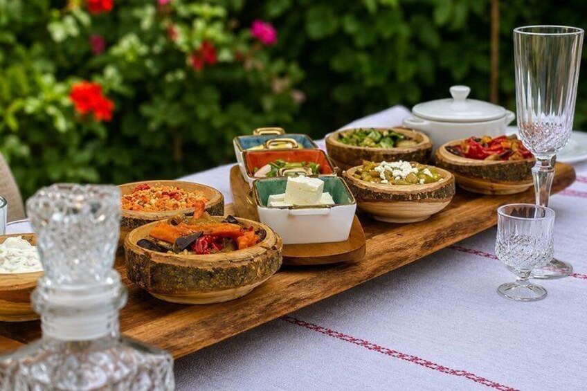 En träbricka med olika sorters mat och glasvaror står på ett bord utomhus. 1