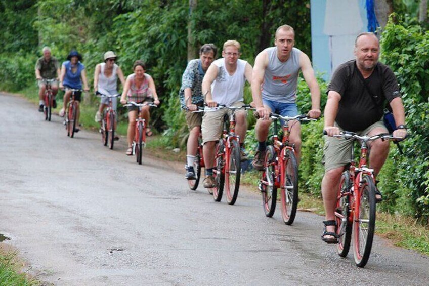 Un grupo de personas pedaleando en bicicleta por un camino pavimentado rodeado de vegetación. 4