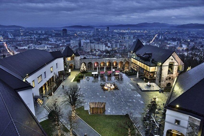 A courtyard with buildings, a fountain, and a cityscape in the background. 5