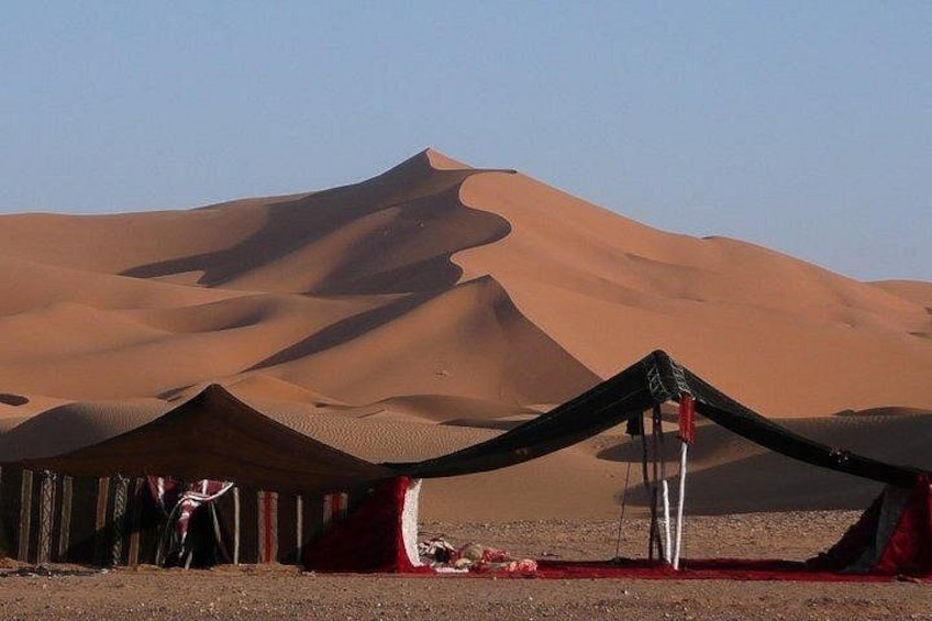 A desert landscape with sand dunes and a tent structure. 2