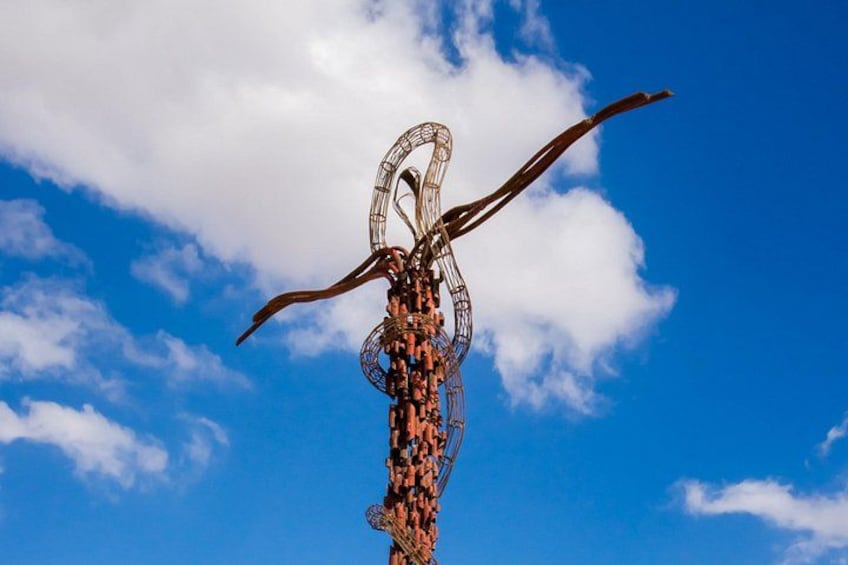 Een hoge sculptuur met grote hoorns voor een blauwe lucht met wolken. 1