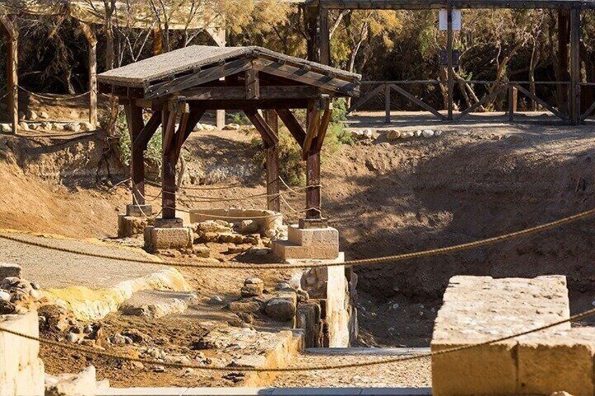 A wooden structure, possibly a shelter, in a dry, rocky landscape with sparse vegetation. 2