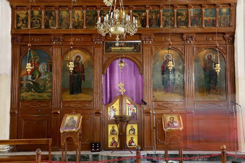 Een rijk versierd kerkinterieur met religieuze iconen, een kroonluchter en een kansel. 4