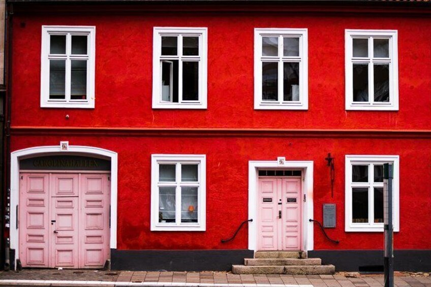 Un bâtiment rouge avec des fenêtres à encadrement blanc et des portes roses. 1
