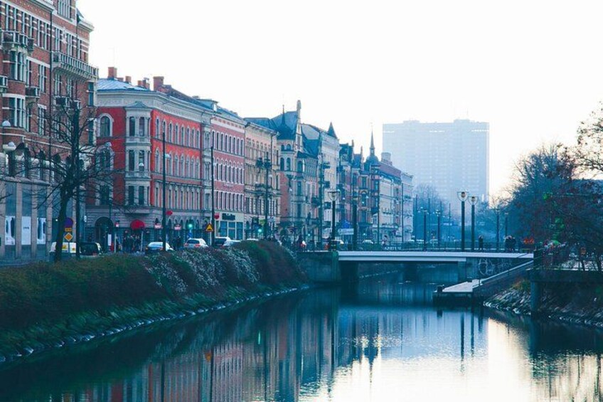 A river with buildings along the banks, a bridge, and a tall building in the background. 2